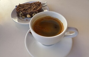 Aromatic black hot coffee in a white cup and chocolate cake