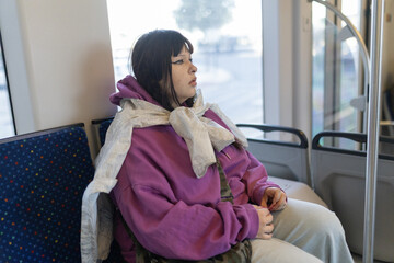 Young person traveling alone on public transport looking outside