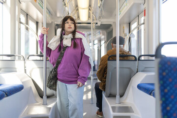 Young woman commuting on public transport standing looking out window
