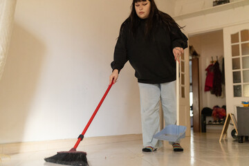 Woman sweeping floor with broom and dustpan