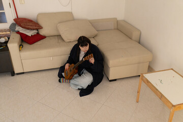 Young woman playing ukulele on living room floor