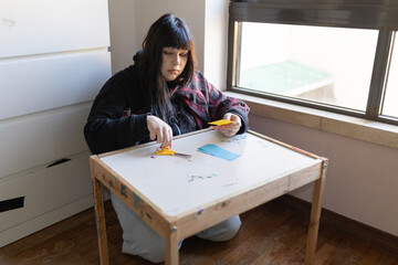 Young woman crafting paper shapes with scissors at home