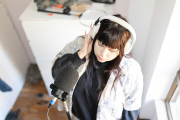 Young woman recording podcast using microphone and headphones