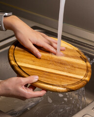 girl washing wooden cutting board at kitchen sink