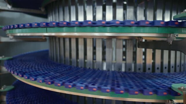 Conveyor system in a factory demonstrating automated item transportation. Blue belts move efficiently along metal tracks, showcasing modern industrial technology in action.