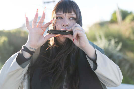 Young woman playing harmonica outdoors at sunset