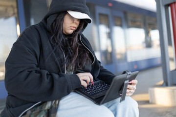 Young woman typing on tablet waiting for train
