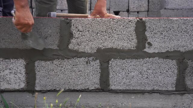 Masonry of concrete blocks and leveling of mortar