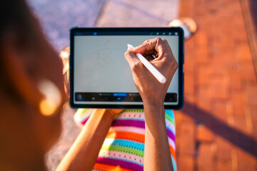 Close-up of African woman’s hand sketching digitally on tablet with stylus, highlighting...