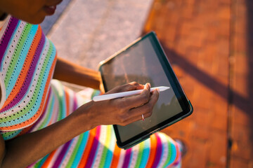Close-up of African woman's hands using stylus on tablet, showcasing tactile control, precision, and the essence of creative interaction with modern digital tools.