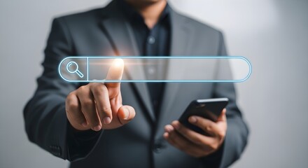 Man in a suit using his finger to select a search bar on a digital interface while holding a smartphone.