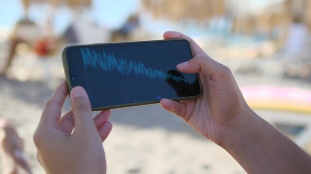 Close up of a mans hands on a beach using a smartphone to analyze a financial chart, actively filtering the data by different time periods. T