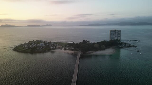 Aerial view of illa de Toralla island featuring a bridge connecting it, with buildings and beaches contrasting against the ocean, illa de Toralla, Pontevedra, Spain.