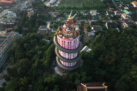 Khlong Mai, Thailand - 29 October 2023: Aerial view of the vibrant Wat Samphran temple, its pink tower embraced by an elaborate dragon spiraling upwards amidst lush greenery.