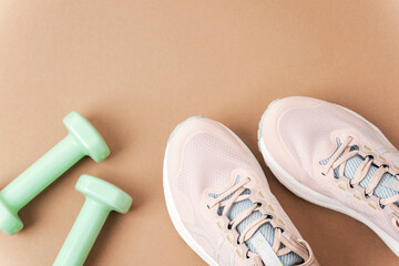 Dumbbells and sneakers on beige background, closeup. Sport, fitness, healthy lifestyle concept. Top...