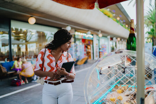 Smiling woman with braids and sunglasses holding smartphone outdoors, symbolizing joy, digital freedom, and empowerment through mobile technology in modern freelance lifestyle.