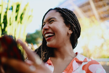Close-up of woman laughing outdoors while holding smartphone, symbolizing joy, empowerment, and confidence in modern freelance lifestyle and digital independence.