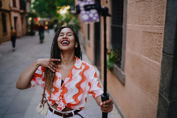 Laughing woman records herself with smartphone on stabilizer, showing joy, empowerment, creativity and self-expression as part of modern influencer lifestyle.