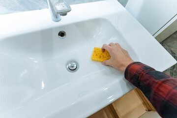 hand cleaning shower threshold and sink junction with yellow sponge, striped curtain and mosaic...