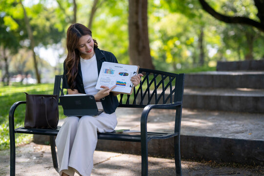 Asian businesswoman presenting financial data outdoors in park