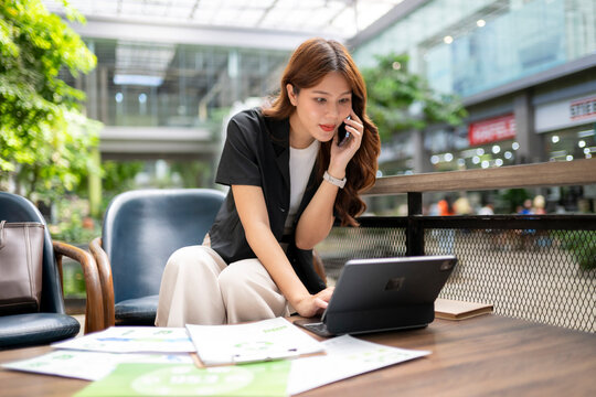 Asian businesswoman multitasking, talking on phone, working on tablet