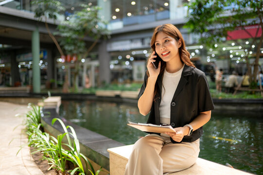 Asian businesswoman making phone call outdoors in urban setting