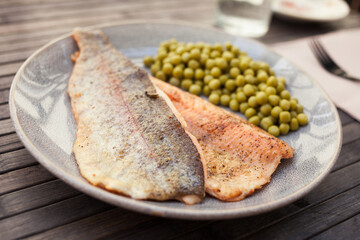 Fried trout fillets served with green peas