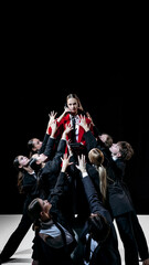 Fototapeta premium Team reaching toward red-clad leader in bold conceptual scene for modern creative marketing visuals. Concept of brand emotion, visual storytelling, eye-catching contrast and high-impact promos.