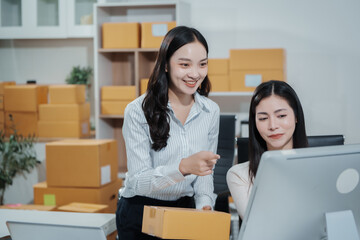 Two Asian women working together in an e-commerce office, managing online orders and shipping logistics while checking product details on a computer,demonstrating teamwork, entrepreneurship,business