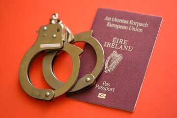 Ireland passport with police handcuffs on table close up. Criminal level and arrests in Europe...