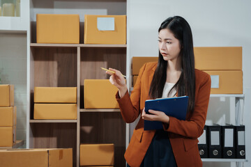 Asian female entrepreneurs coordinating product handover at an e-commerce office, preparing parcels for shipping logistics while collaborating professionally to manage online business operations