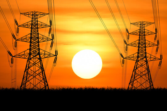 Electric Towers Silhouetted Against a Sunset, Power Lines Against the Warm Sky. The image features electricity pylons set against a warm and inviting background - Powered by Adobe
