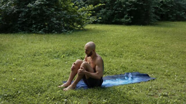 Man performing smooth mobility and roll transitions barefoot outdoors
