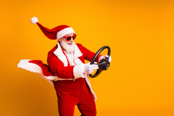 Santa drives a fun festive promo image wearing red costume cape and steering wheel yellow background for Christmas family holiday vibe
