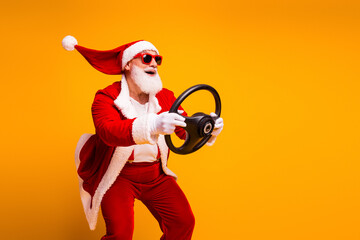 Santa in a red suit with a steering wheel poses joyfully against a bright orange background for a...