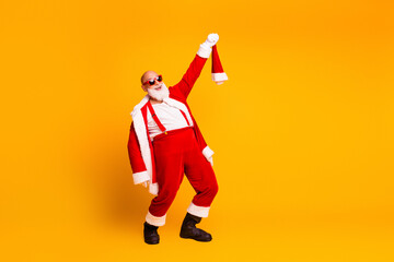 Santa in red suit dances with his hat raised against a bright yellow background for a festive holiday mood perfect for Christmas season promotions and family celebration