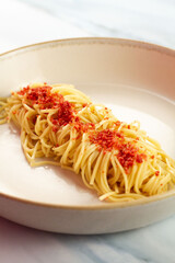 Homemade spaghetti aglio e olio with garlic, crispy flakes and parmesan cheese served on a white plate, a delicious Italian pasta dish.