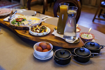 A long wood board holds sliced meats, cheeses, and garnished spreads by salads, three mini cast...