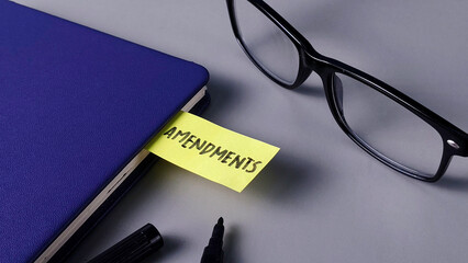 Amendments Note in Blue Notebook with Glasses: Legal Change, Policy Review, and Editing Concept