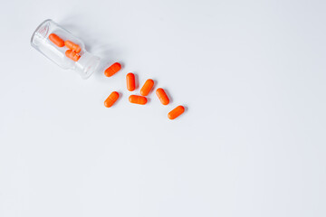 orange pills in glass bottle on white background