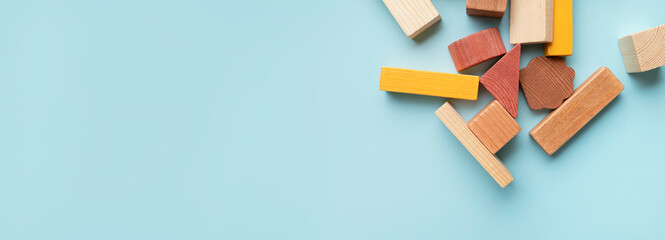 Montessori style cubes game for toddlers flat lay top view. Wooden children's construction set blocks of different shapes natural colors on blue background. Concept of learning and education