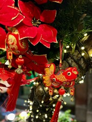 Vibrant red holly flowers decorations featuring a traditional fish ornament, surrounded by festive lights, creating a joyful atmosphere for celebrations and cultural festivities. Vertical background 