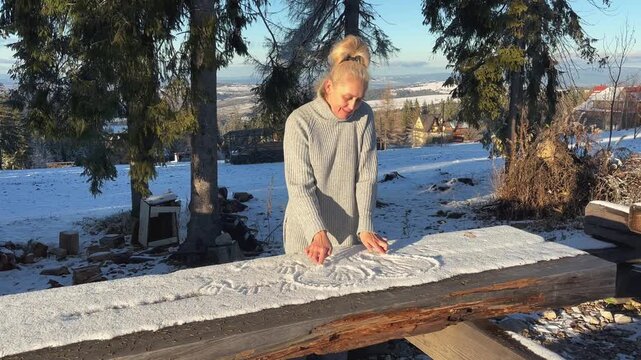 Woman draws handprints in fresh snow
