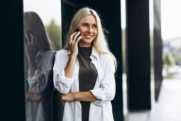 Young woman talking on the phone, standing by the business center