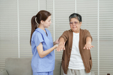 Obraz premium Senior asian woman raising arms forward under guidance of female asian physiotherapist during arm mobility recovery session focusing on joint flexibility and strength training