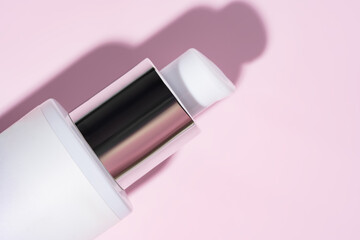 Cosmetic product, pump cream bottle lying on pink background. dispenser close up