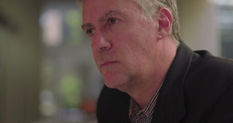 Close-up of middle aged man deep in thought in office lounge, resting chin on hand with focused expression during moment of introspective decision making