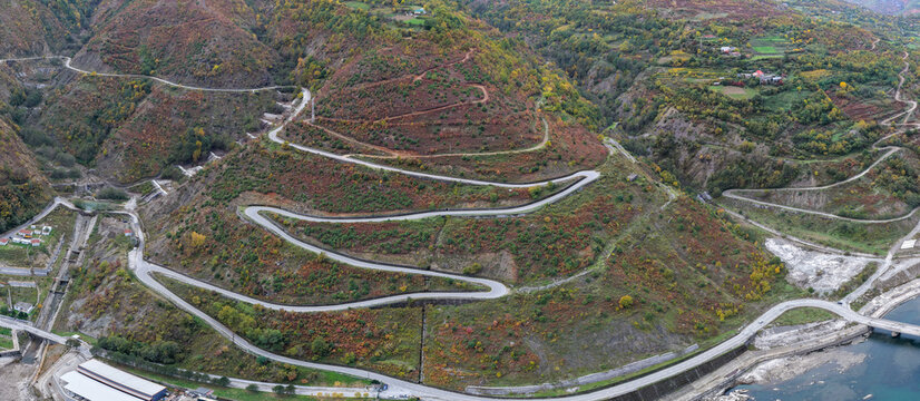 Aerial view of winding mountain switchbacks near Fierz&euml;, surrounded by rugged autumn slopes and scattered homes.