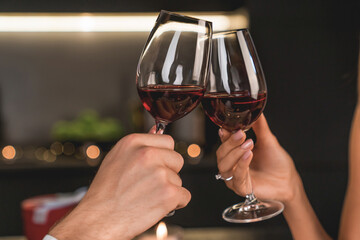 Close up shot of man and woman toasting and drinking red wine from glasses on dinner. Alcohol drinks cropped image. Special event celebration, Valentine`s day, anniversary