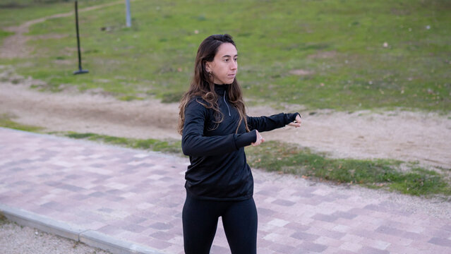 Woman practicing tai chi in park outdoors, finding balance and concentration through traditional martial arts